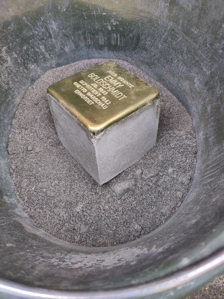 Der Stolperstein für Emmy Goldschmidt wartet in einem Eimer auf seine Verlegung.