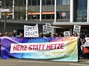 OMAS GEGEN RECHTS tragen ein buntes Banner mit dem Text „Herz statt Hetze“, außerdem viele OMAS-Plakate.