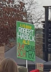 Demoplakat auf grünem Grund: "Lieber Robert Habeck als Olaf Friedrich Sch-Merz"