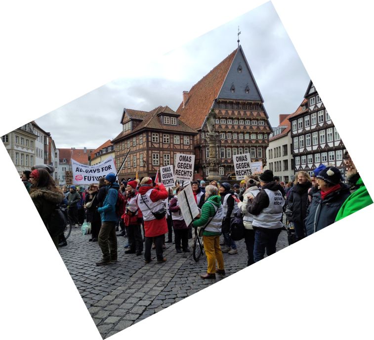 Schräg fotografierter Blick über den hübschen Hildesheimer Marktplatz mit Menschenmenge. Über den Köpfen ragen Schilder hoch: "All days for future" und "Omas gegen Rechts".