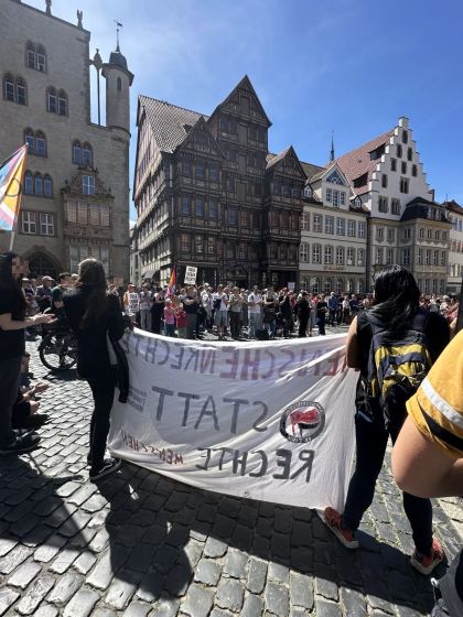 Menschen auf dem Hildesheimer Marktplatz demonstrieren für das AfD-Verbot. Im Vordergrund ein großes Transparent, das man aber nur von hinten sieht.