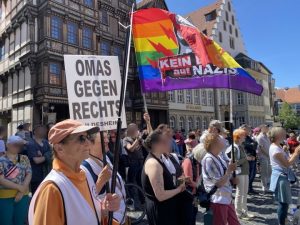 Auf dem Hildesheimer Marktplatz stehen Menschen mit Schildern und Fahnen. Auf einem Schild steht OMAS GEGEN RECHTS Hildesheim.