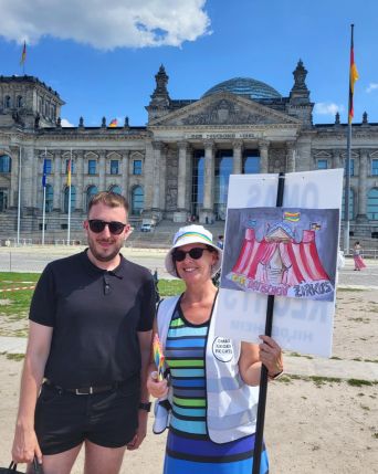 Eine Hildesheimer OMA mit Maik Brückner, dem queerpolitischen Sprecher der Linken. Die OMA hält ein Plakat mit einem reichstagsähnlichen Zirkuszelt, auf dem eine Regenbogenfahne weht.