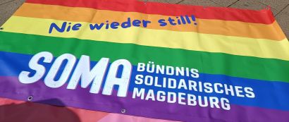 Demo-Banner des SOMA Magdeburg: Auf Regenbogenfarben steht "Nie wieder still!"