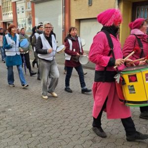 Am rechten Bildrand zwei in Pink gekleidete Mitglieder der Trommelgruppe "Rhythms of Resistance". Es folgen einige OMAS GEGEN RECHTS mit diversen Trommelinstrumenten.