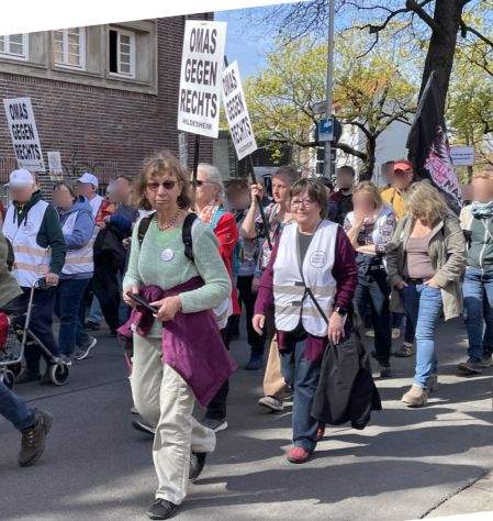 Ein Demonstrationszug mit einigen OMAS GEGEN RECHTS geht an einem Frühlingstag durch eine Stadt.