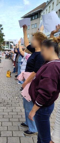 Menschen stehen in einer langen Reihe und halten weiße Papierblätter hoch. Auf einigen steht "GG Art 20a".